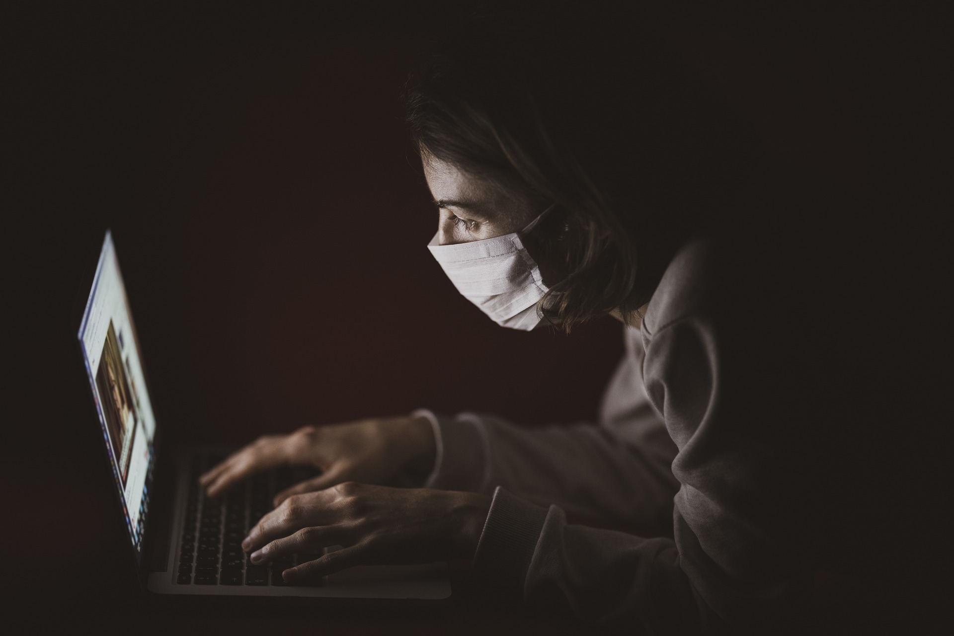 暗闇でパソコンを操作している人の写真