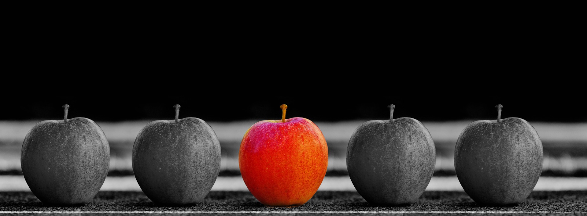 横に並べられたリンゴの白黒写真に一つだけ色が着いている
